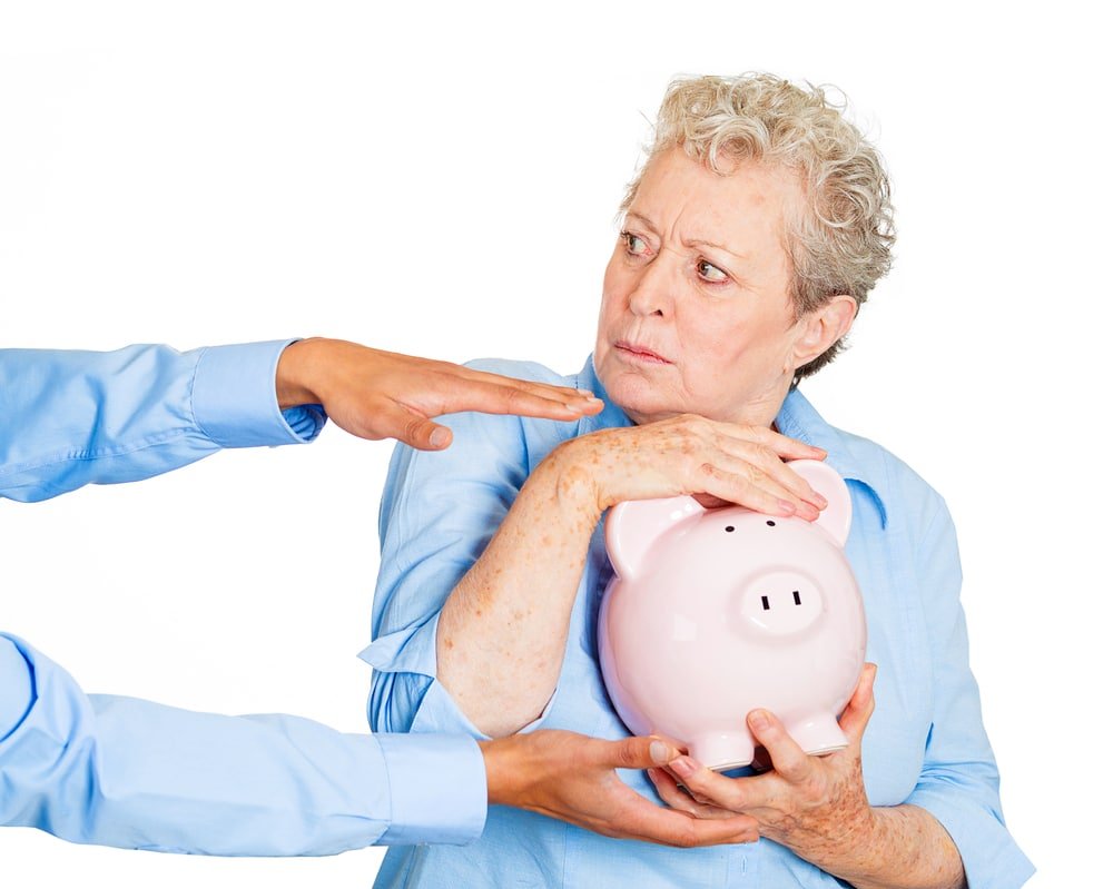 Lady in blue shirt clutching piggy bank while someone else reaches for it