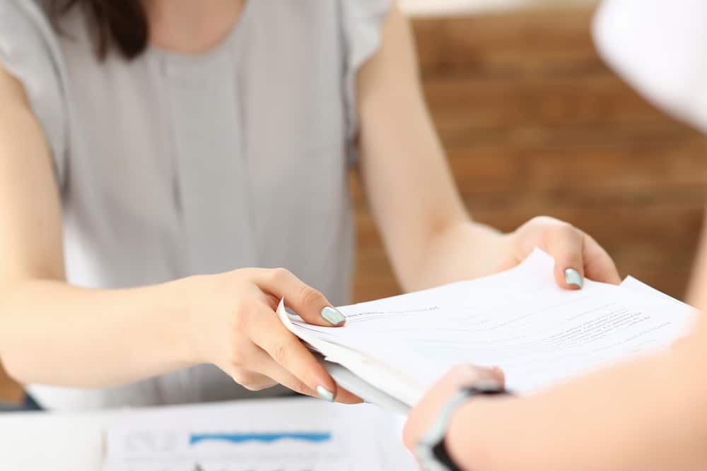 Woman handing another person paperwork