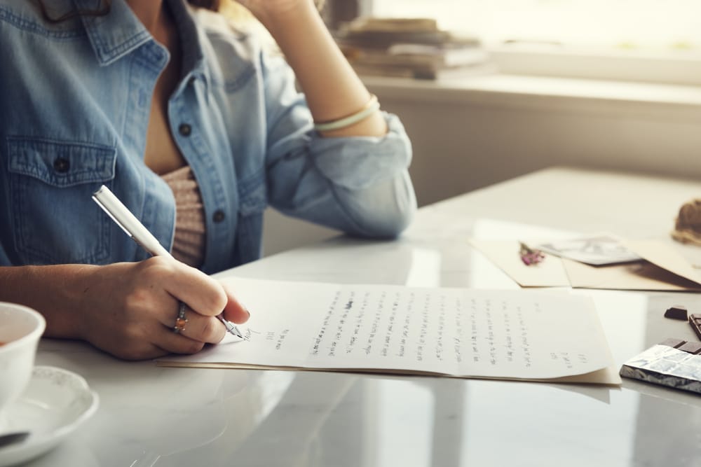 Woman sitting at a table and writing a letter