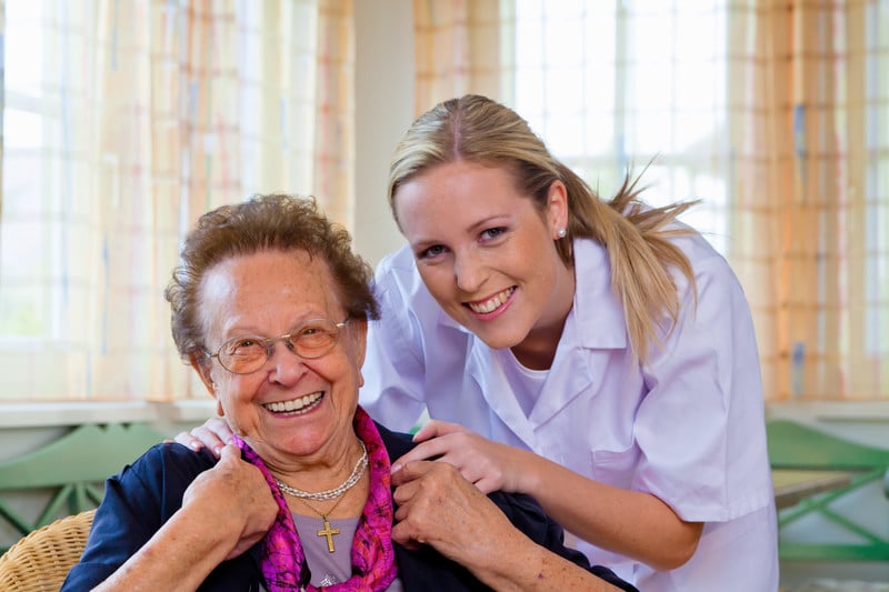 Senior woman smiling with a nurse at assisted living facility