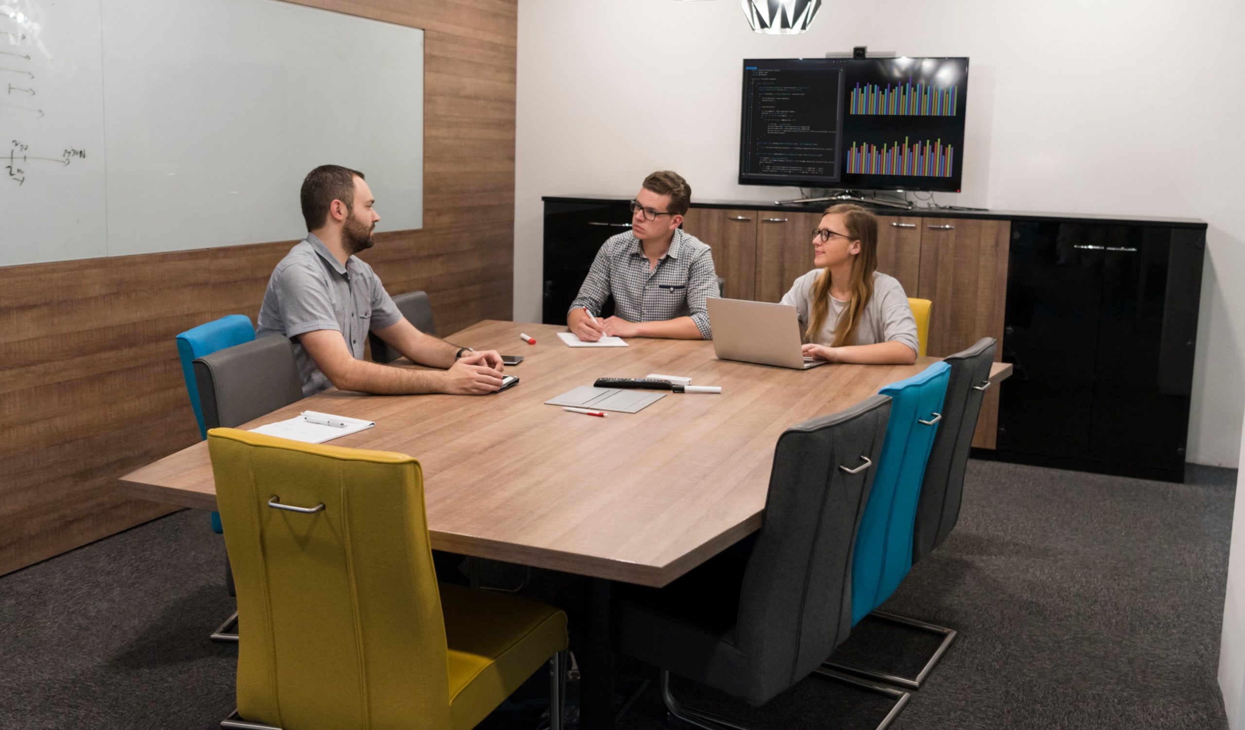 Three people sitting around a conference room table